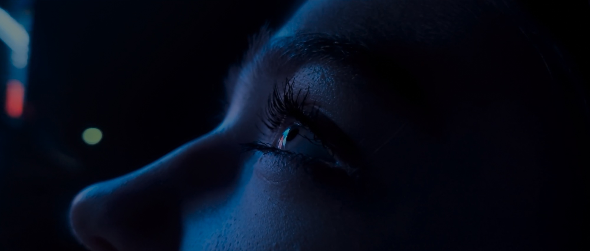 Close-up of an eye lit in deep blue with red neon reflections, from 'After Dark' for Sony Xperia