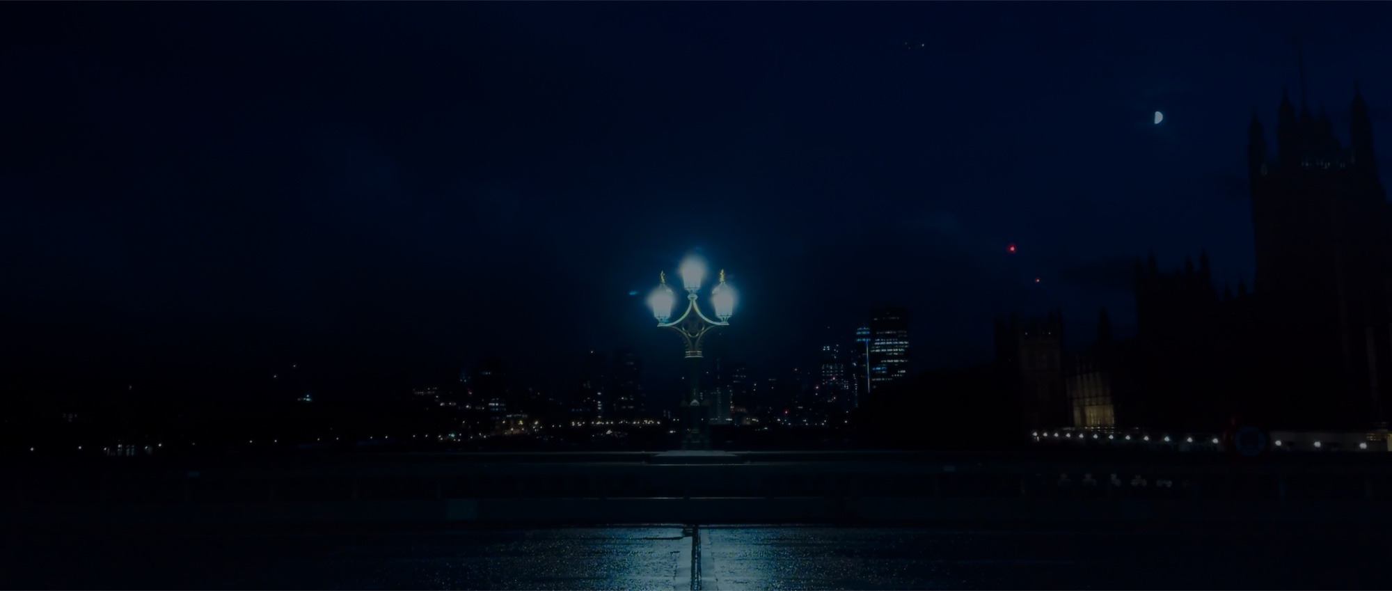 The Thames at night, a lamp post on the embankment and Westminster in the distance