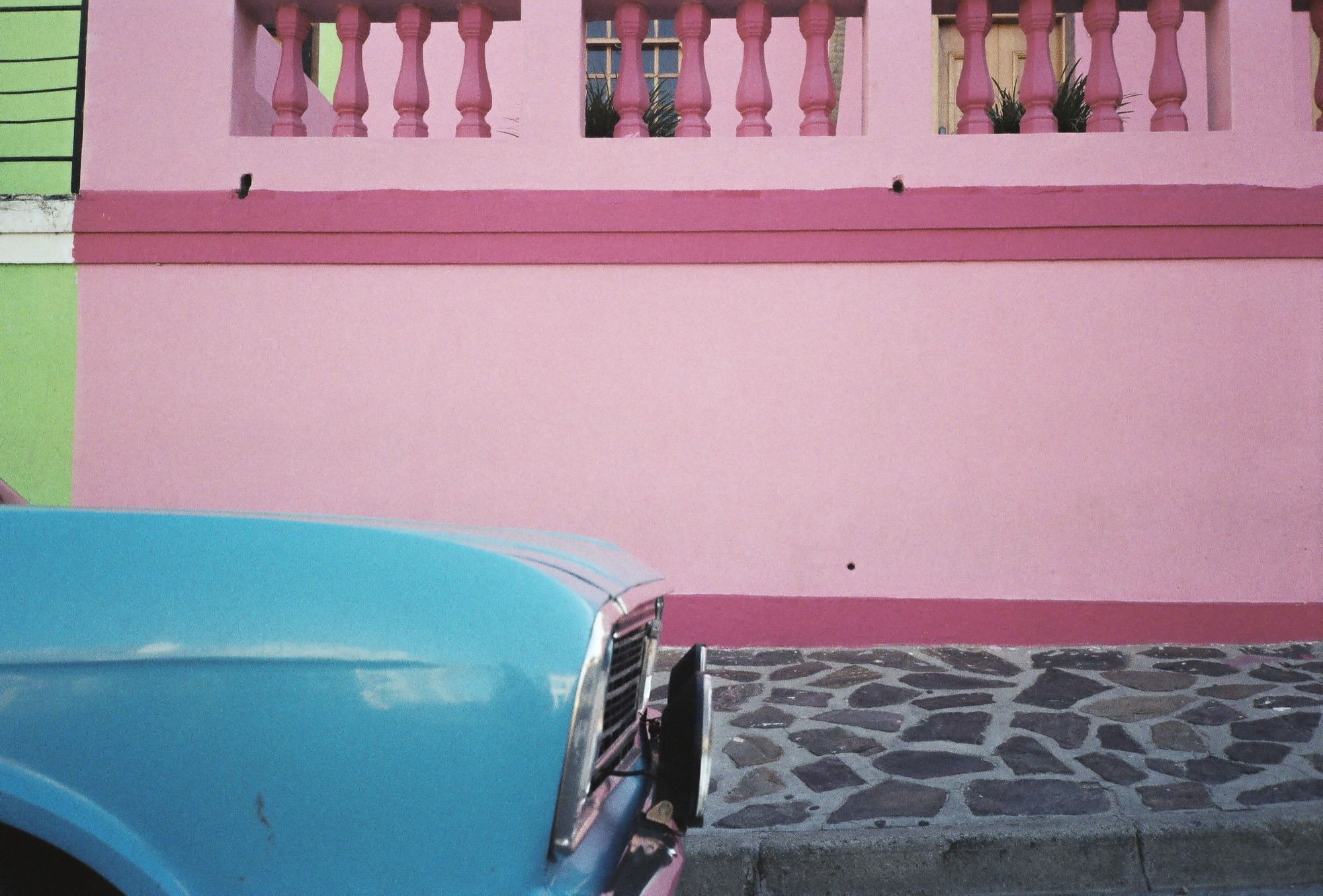 Pink and green houses in Bo-Kaap with a blue vintage car
