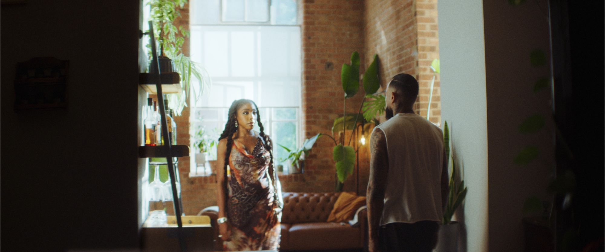 Two figures in a warm brick loft interior with soft window light, from Nissi's 'Lock & Key' music video