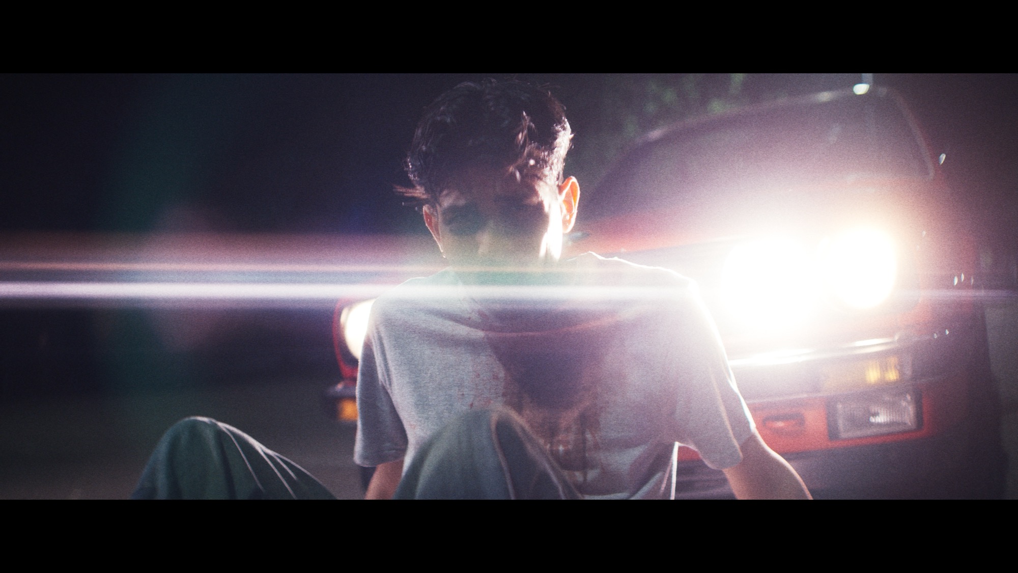 Man on the ground caught in a car's headlights at night, from WhotfisArya's 'Lovesick'