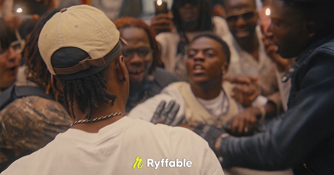 Crowd celebrating around a man in a cream cap