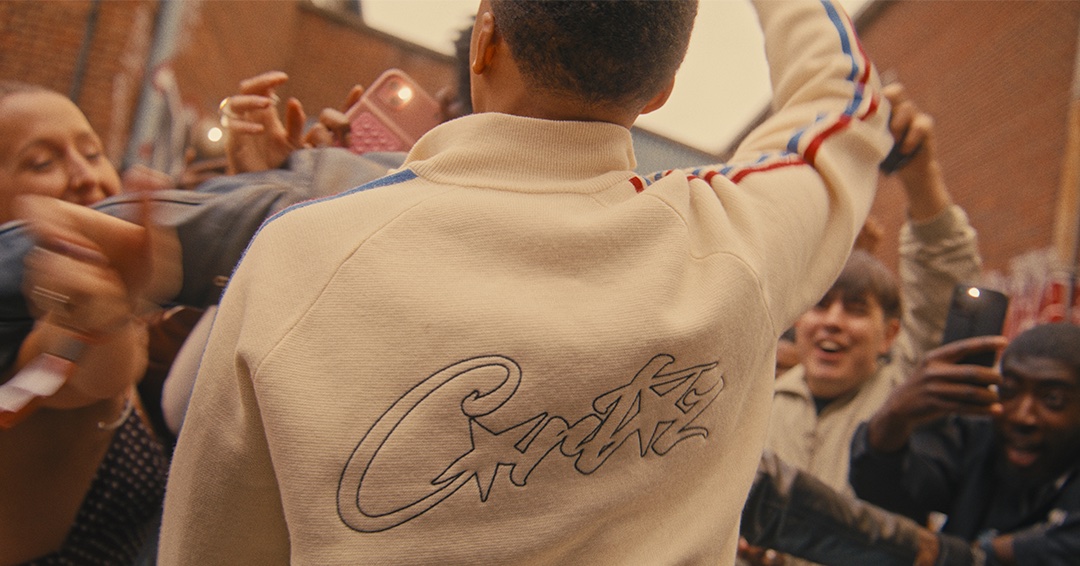 Man in a cream jacket with his back to camera as the crowd cheers