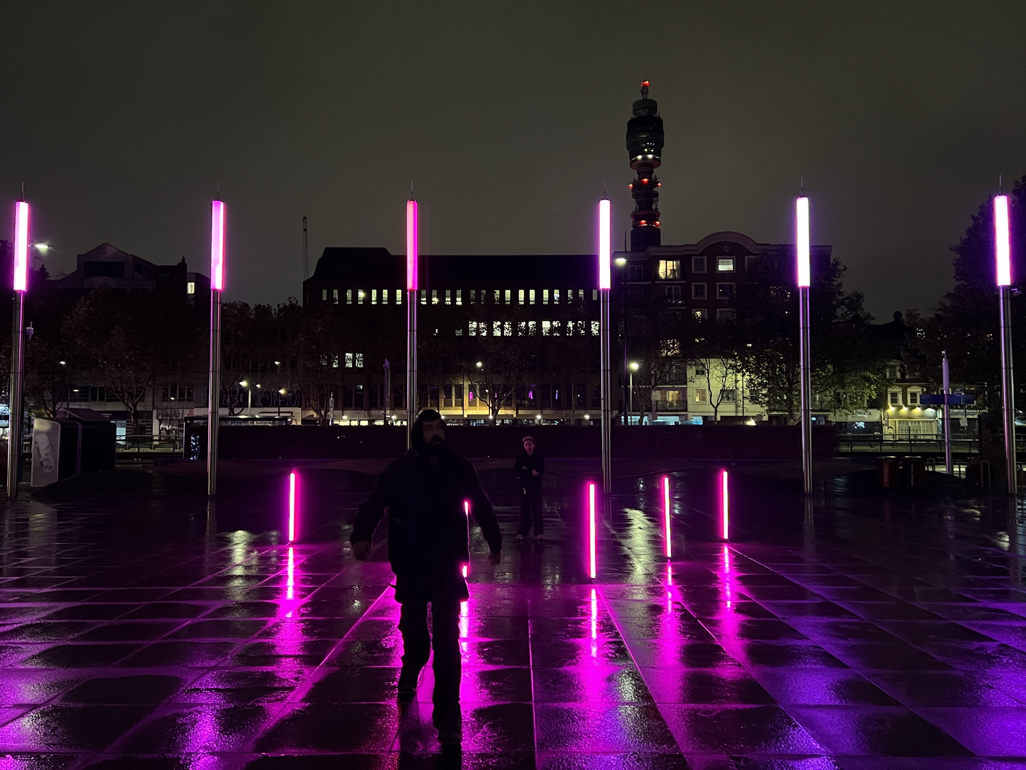 The plaza at night with the pink neon poles set