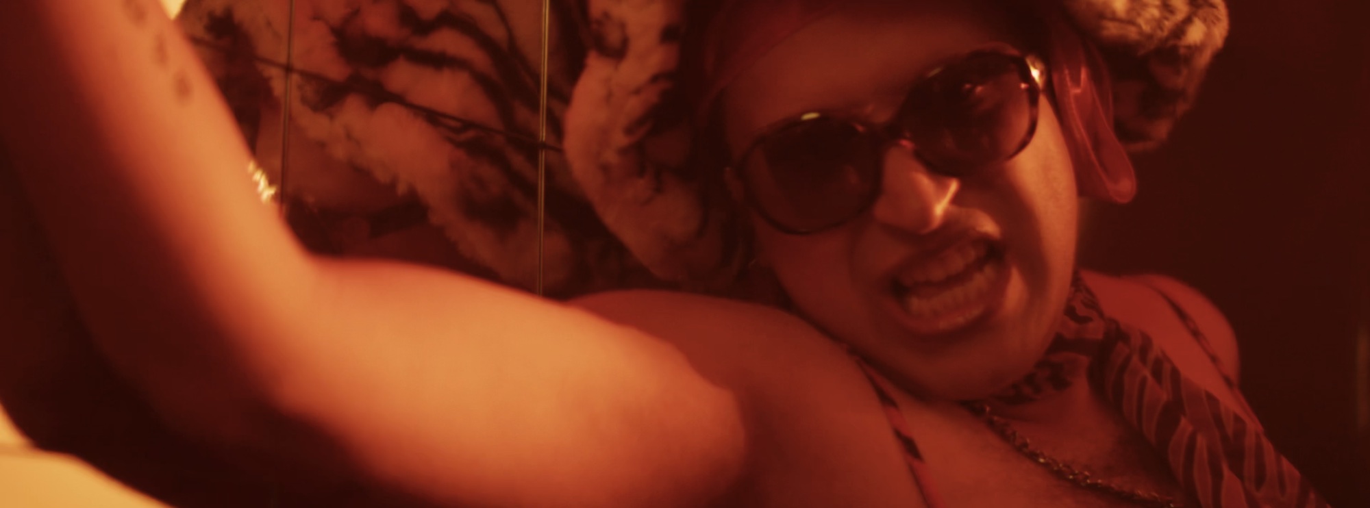 Performer in sunglasses in hard red light, from Comanavago's 'Say Less'
