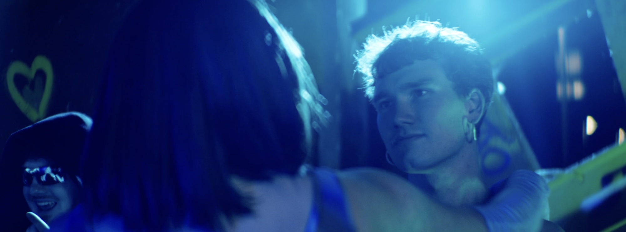 Two dancers in blue light, one caught in a lens flare