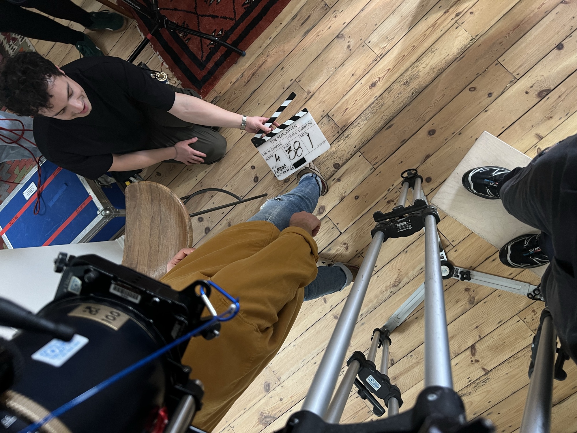Slate up on the wooden floor, crew around the actor